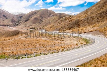 New Zealand Desert Mountain Pass:  A two lane highway curves through arid terrain toward Lindis Pass on New Zealand South Island.