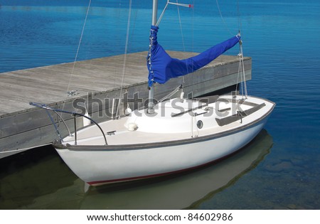 Small Sailboat:  A small white boat waits at a wooden dock.