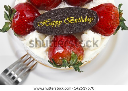 strawberry butter cream cake with birthday chocolate plate & fork on white