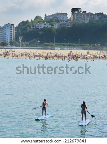 SUP, Paddle surf in the beach with boats in background.