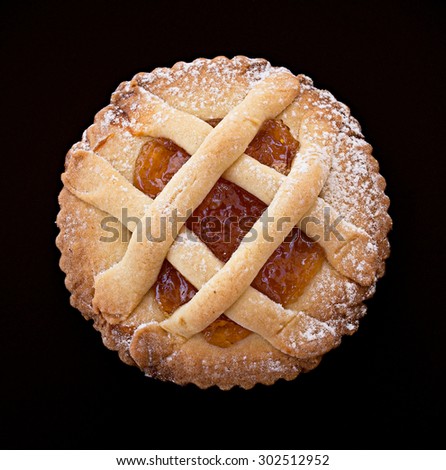 Short pastry tartlet with marmalade isolated on black.