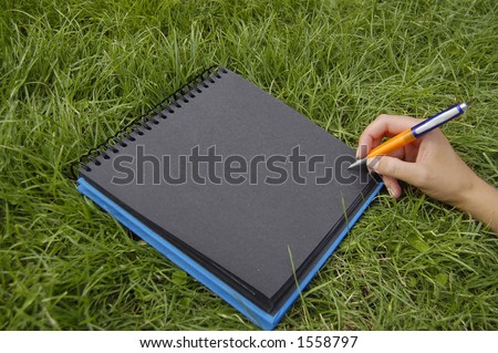 black notebook in grass writing
