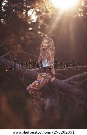 Portrait of woman in the forest. Beautiful blonde woman leaning against a tree in the sunset light