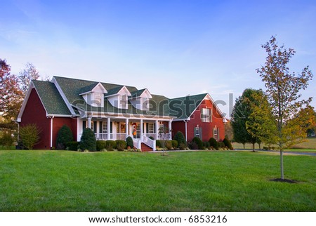 A large brick house in the country at dusk.