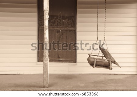 An old swing on the front porch of an abandoned house.