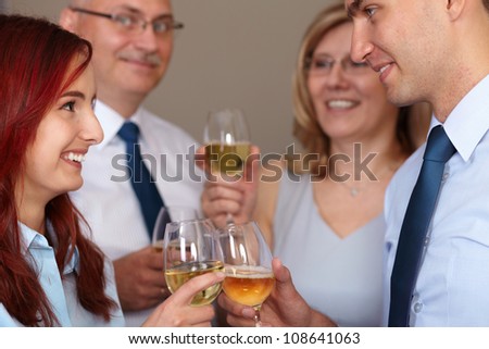 Group of 4 younger and older businesspeople celebrate with wine glasses in their hands
