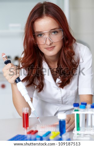 Young female lab technician work with pipette and some tubes, lab shot