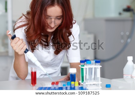 Young female lab technician work with pipette and some tubes, lab shot
