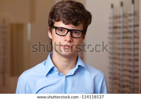 Young attractive man at optician with glasses, background in optician shop