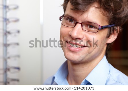 Young attractive smiling man at optician with glasses, background in optician shop