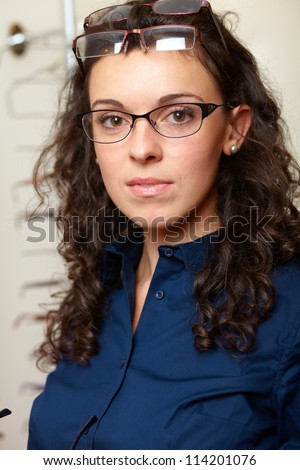 Young attractive smiling woman at optician with glasses, background in optician shop