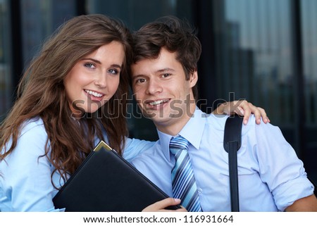 Close portrait of a smiling attractive business young couple with briefcase, background