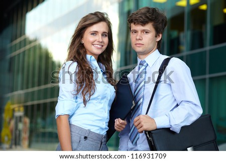 Portrait of a smiling attractive business young couple with briefcase, background