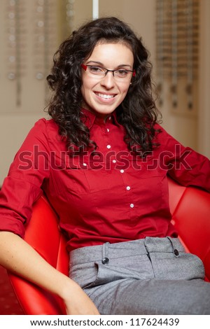 Young attractive smiling woman at optician with glasses, background in optician shop