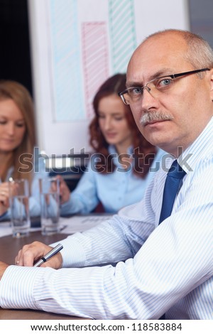 Senior businesswoman sitting on a business meeting with younger colleagues, background in the office