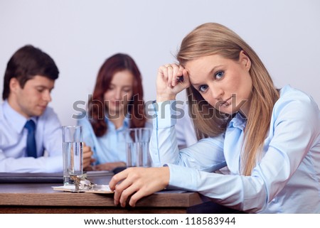 Young attractive tired businesswoman on a business meeting, background in the office