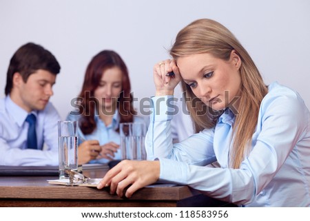 Young attractive tired businesswoman on a business meeting, background in the office