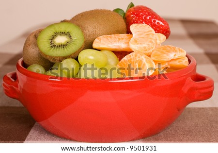 fruit composition in red bowl, kiwi, grapes, orange, strawberry and other fruits