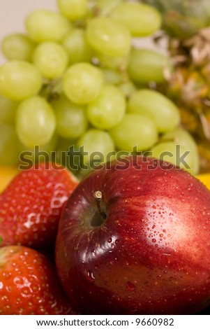 red apple in focus with grapes and strawberry as background