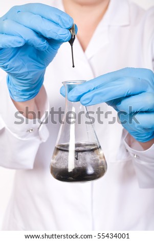 lab assistant making some laboratory tests, black fluid dropped into test tube filled with water,
