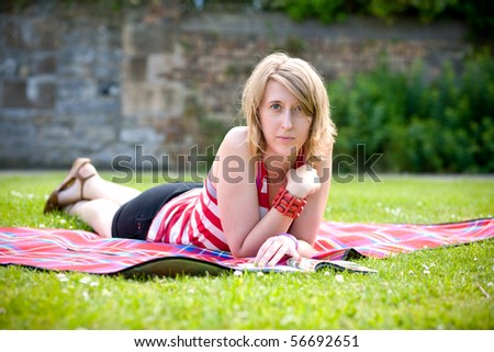 young attractive female reads magazine while getting some rest in the park, outdoor shoot