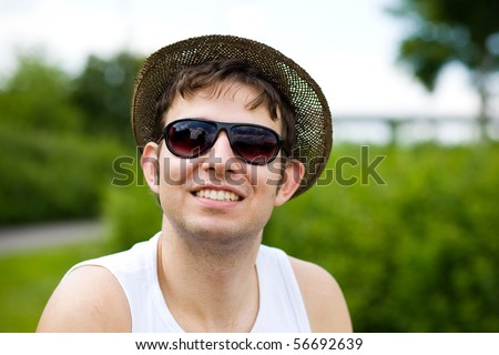 young attractive male in the park with hat and sunglasses, outdoor portrait