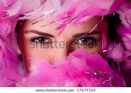 closeup photo of beautiful woman eyes with pink feather boa around her face, studio shoot