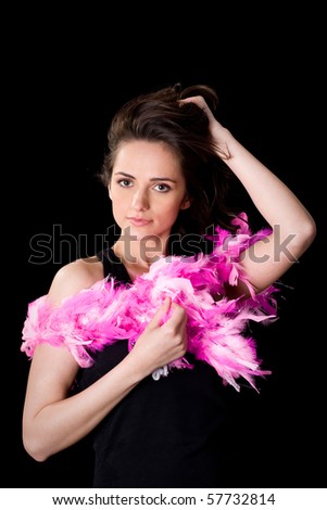 young attractive woman holds her hair above her head, and pink boa wrapped around her arms, studio shoot isolated on black background