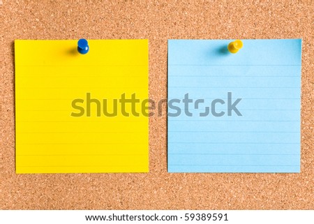 blue and yellow stripped notes attached by yellow and blue pins on cork board