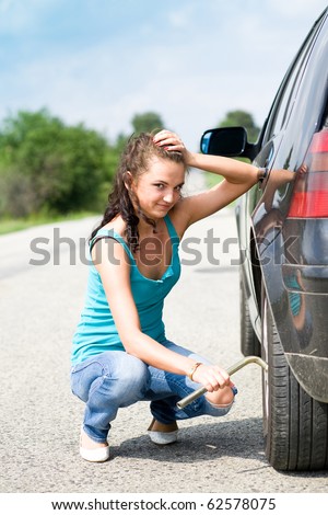 helpless young woman try to change wheel in her car