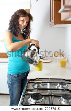 young attractive female student makes tea in kitchen