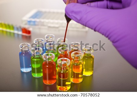 laboratory colorful test tubes, pipette with red fluid over one of the bottles, science, experiment
