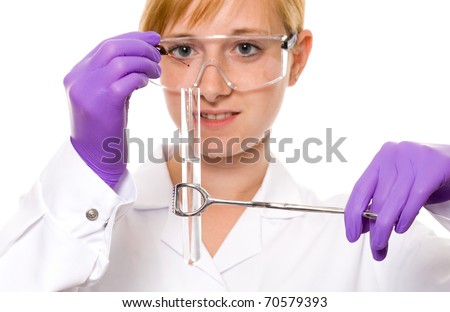 young female scientist holds test tube using tongs, also dropping some red fluid to the tube, wears gloves and goggles, studio shoot isolated on white background