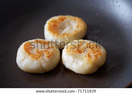 three dumpling being heated on oiled pan