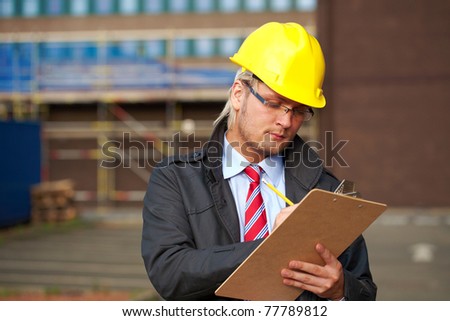 young architect or inspector make some notes, office building as blurred background