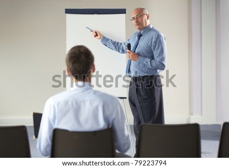 senior manager during seminar, presentation, point to white board and hold microphone, indoor shoot