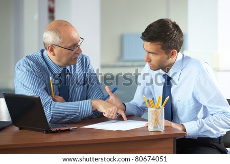 senior and junior businessman discuss something during their meeting, office background