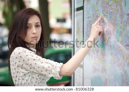young attractive female reads map, confused looking for something on the city plan