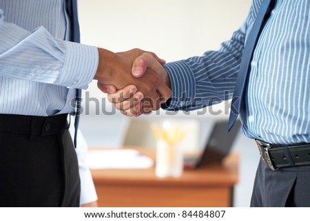 two male hands in business handshake, both wear blue shirts
