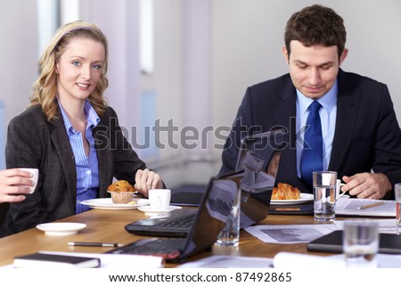 Young businessman and businesswoman sitting at conference table have a break during meeting