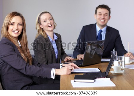 Three business people sitting at conference table and have a laugh