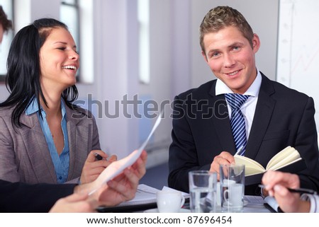 Two young business people sitting at table and have laugh while working on some paperwork