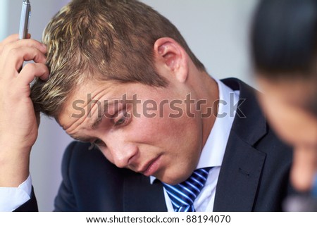 Young worried and stressed businessman scratch his head