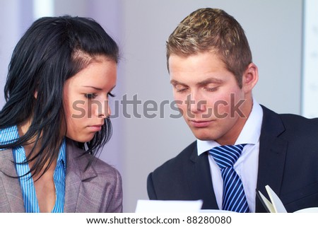 Two young business people sitting at table and have laugh while working on some paperwork