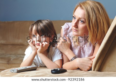 Young mother with her son watch tv, sad and serious face expression