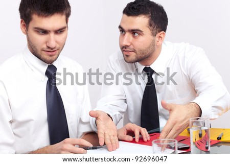 Two businessman have an argument over some paperwork.
