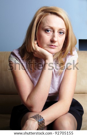 Young sad and unhappy female sits on sofa