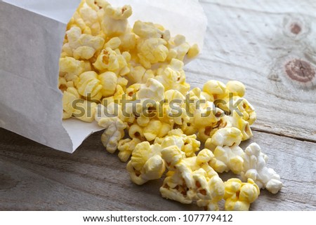 Popcorn spilling from plain white bag onto picnic table