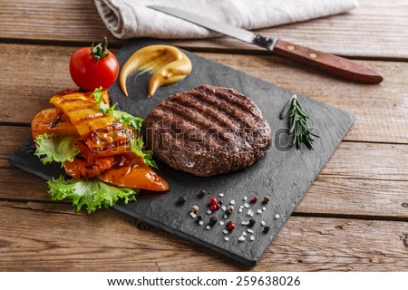 burger grill\
with vegetables and sauce on a wooden surface