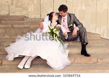 Happy bride and groom sitting on stairs outdoor